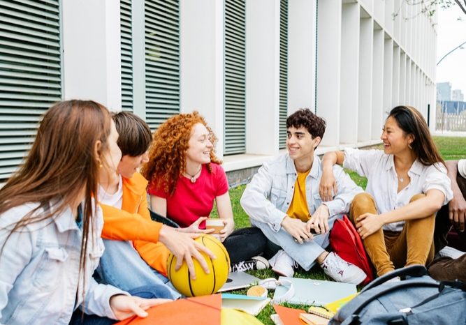 Students,Of,Ethnic,Diversity,Sitting,On,The,Campus,Lawn,With Students,Of,Ethnic,Diversity,Sitting,On,The,Campus,Lawn,With